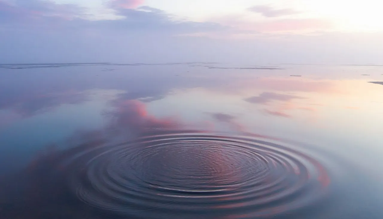 Ondas suaves en la superficie de un lago tranquilo que refleja un cielo rosado