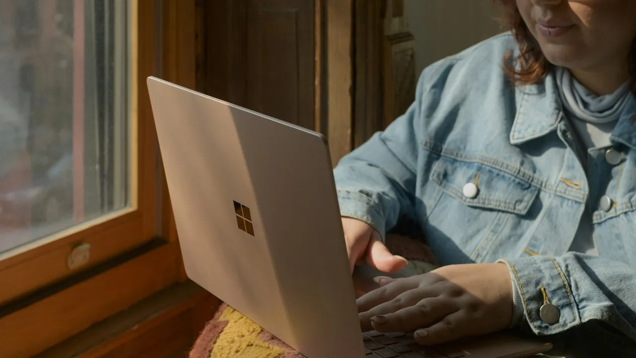 Mujer sentada tranquila en un sillón usando su laptop en casa con luz natural